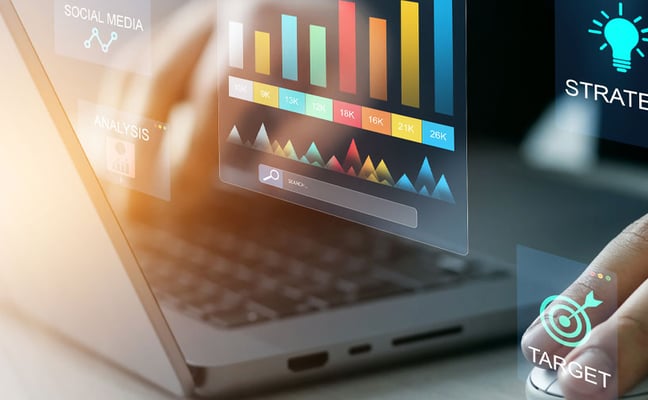 Hand on laptop keyboard with holographic business analytics displays showing charts, strategy, brand, and target icons